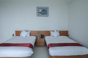 two twin beds in a room with white walls at JAKAS Resource Center in Helkunda