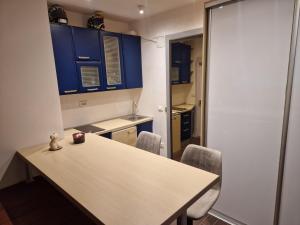 una cucina con armadi blu, tavolo e sedie di Jacuzzi Vaki Apartment a Belgrado