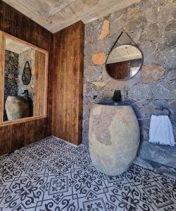 a stone bathroom with a tub and a mirror at My hell Village in Tijarafe