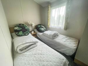 Habitación con 2 camas y ventana en Beautiful 6 Berth Caravan With Decking In Norfolk Ref 89001mv en Belton