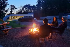 3 Leute sitzen um ein Feuer im Garten herum in der Unterkunft GF Studio, Secure parking, outside area, cinema(S) in Hurn