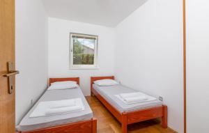 two beds in a room with a window at Apartments Dunja Malinska in Malinska