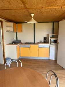 a kitchen with yellow cabinets and a table and chairs at La vallée 2 in Belvédère