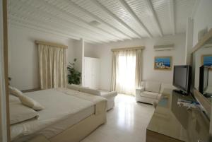 a white room with a bed and a tv at Dionysos Luxury Hotel Mykonos in Ornos