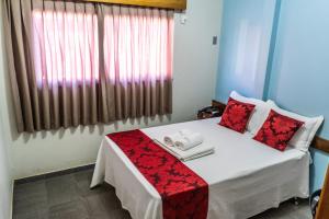 a bedroom with a bed with red pillows and a window at Pousada Paraiso in Guanambi