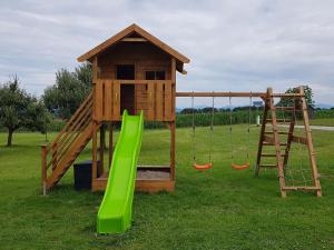 a wooden play structure with a slide and swings at Feichtlhof in Taching am See