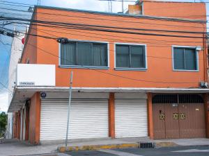 un bâtiment orange avec deux portes de garage dans une rue dans l'établissement Cómodo Departamento Privado Aeropuerto 7 Min caminando, à Mexico