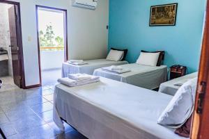 two beds in a room with blue walls at Pousada Paraiso in Guanambi