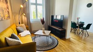 een woonkamer met een gele bank en een tv bij Apartment FLORA in Halle an der Saale in Halle an der Saale