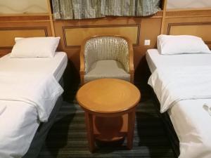 a room with two beds and a table and a chair at فندق منار التوحيد 1 in Makkah