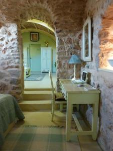 ein Schlafzimmer mit einem Schreibtisch in einer Steinmauer in der Unterkunft St. George Sykoussis Traditional Residence in Ágios Geórgios Sykoúsis