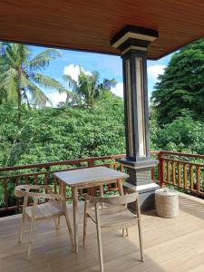 una mesa de madera y una silla en el porche en Karma House en Ubud