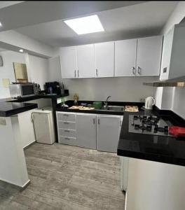 una cucina con armadi bianchi e piano di lavoro nero di Inviting 1-Bed Apartment in Ksar sghir a Ksar es-Seghir