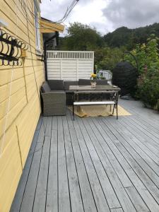 a patio with a couch and a table on a deck at Basement Apartment Varadero in Lyngdal