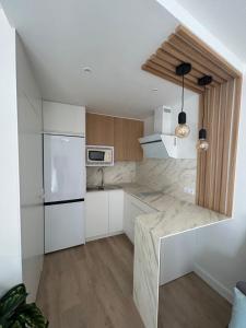 a kitchen with white cabinets and a white refrigerator at Apartamento Chipiona Playa in Chipiona