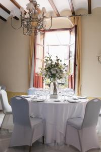 a white table with chairs and a vase of flowers at Hotel Alcázar de la Reina in Carmona