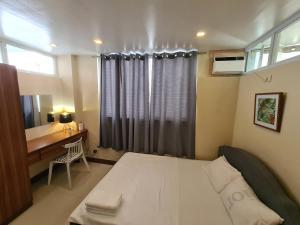 um quarto com uma cama, uma secretária e uma janela em Serenity Home near Ayala Malls Serin em Tagaytay