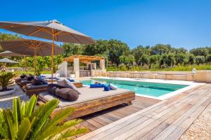 a swimming pool with a bed and an umbrella at Villa Gufo in Ostuni