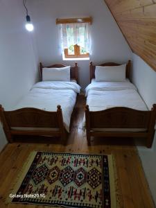 two twin beds in a room with a rug at Mountain Vista Guesthouse Shkafi in Shkodër