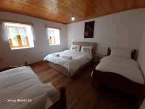 a bedroom with two beds and two windows at Mountain Vista Guesthouse Shkafi in Shkodër