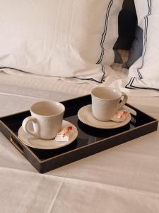 zwei Tassen und Untertassen auf einem Tablett auf einem Bett in der Unterkunft Harmony in everything in Athen
