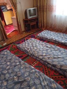 Zimmer mit 3 Betten und einem TV in der Unterkunft Song Kol Flex Travel guests house in Dzhangyaryk
