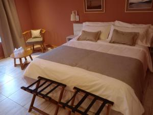 a bedroom with a large white bed and a chair at Hostería Las Semillas in Villa La Angostura