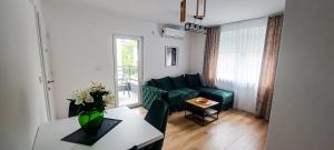 Una sala de estar con un sofá verde y una mesa. en La Casa Apartments, en Jagodina