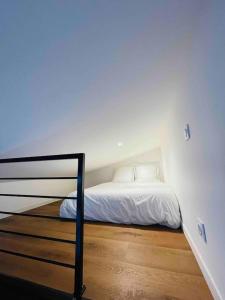 Schlafzimmer mit einem Bett mit weißer Bettwäsche und Holzböden in der Unterkunft Loft - Centre Ville in Brest
