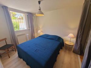 ein Schlafzimmer mit einem blauen Bett und einem Fenster in der Unterkunft Petit Beaucours in Sanary-sur-Mer