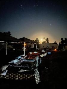 eine Gruppe von Betten in einem Hof in der Nacht in der Unterkunft Camp Sahara Dunes in M’hamid El Ghizlane