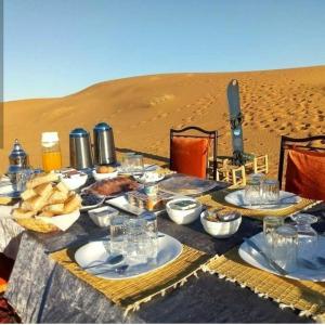 una mesa en el desierto con comida. en Camp Sahara Dunes, en Mhamid