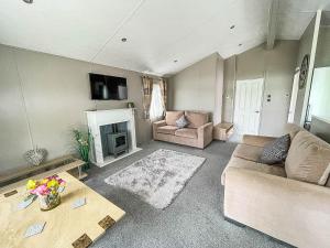 een woonkamer met een bank en een open haard bij Stunning Lodge With Decking At Oaklands Holiday Park In Essex Ref 39017rw in Clacton-on-Sea
