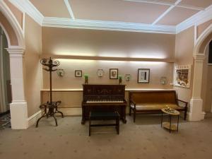 a living room with a piano and a couch at Green Gables Hotel in Scarborough