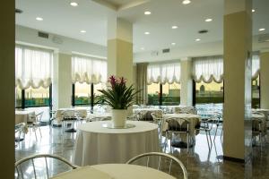 ein Restaurant mit weißen Tischen und Stühlen und einer Pflanze in der Unterkunft Hotel Nord Est in Rimini