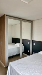 1 dormitorio con 2 camas y un espejo grande en Loft Confortável e Luxuoso ao lado do Shopping CG., en Campo Grande