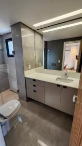 a bathroom with a toilet and a sink and a mirror at Loft Confortável e Luxuoso ao lado do Shopping CG. in Campo Grande