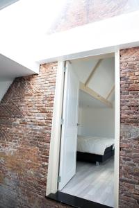 a brick walled bedroom with a bed and an open door at La Casita bed and breakfast in Voorschoten