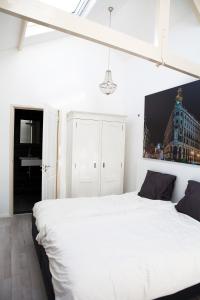 1 dormitorio con cama blanca y ventana en La Casita bed and breakfast, en Voorschoten