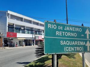 a green street sign in front of a building at Estúdio em Bacaxa in Saquarema