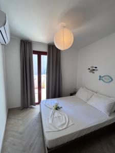 a bedroom with a white bed and a chandelier at Elena Limnos Beach in Volissos