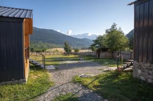 a yard with a building and a fence and mountains at Mestia Villas in Mestia