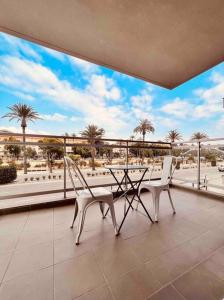 2 sedie e un tavolo sul balcone con palme di Apartamento céntrico con plaza de garaje y piscina a Murcia