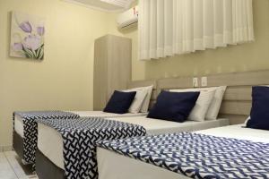 three beds in a room with blue and white sheets at Polar Rio Hotel in Sao Paulo