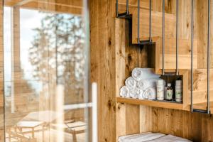 a room with a wooden wall with a shelf with towels at Brandlalm Chalets in Gundisch