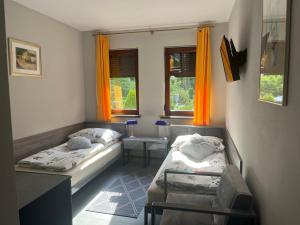 um quarto com duas camas, uma mesa e janelas em Spalskie Pokoje Gościnne em Spała
