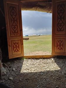 an open door with a view of a field at Song Kol lake, Flex Travel yurt camp, horse riding in Song-Kul