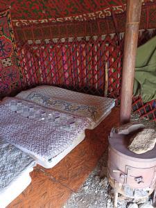 a bed in a tent with a stove in a room at Song Kol lake, Flex Travel yurt camp, horse riding in Song-Kul