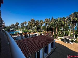 Blick auf ein Resort mit Palmen und einem Dach in der Unterkunft Modern apartment in front of the Mediterranean in Oropesa del Mar
