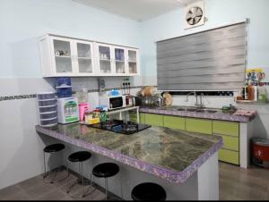 a kitchen with a counter with stools in it at Andi Homestay in Sandakan